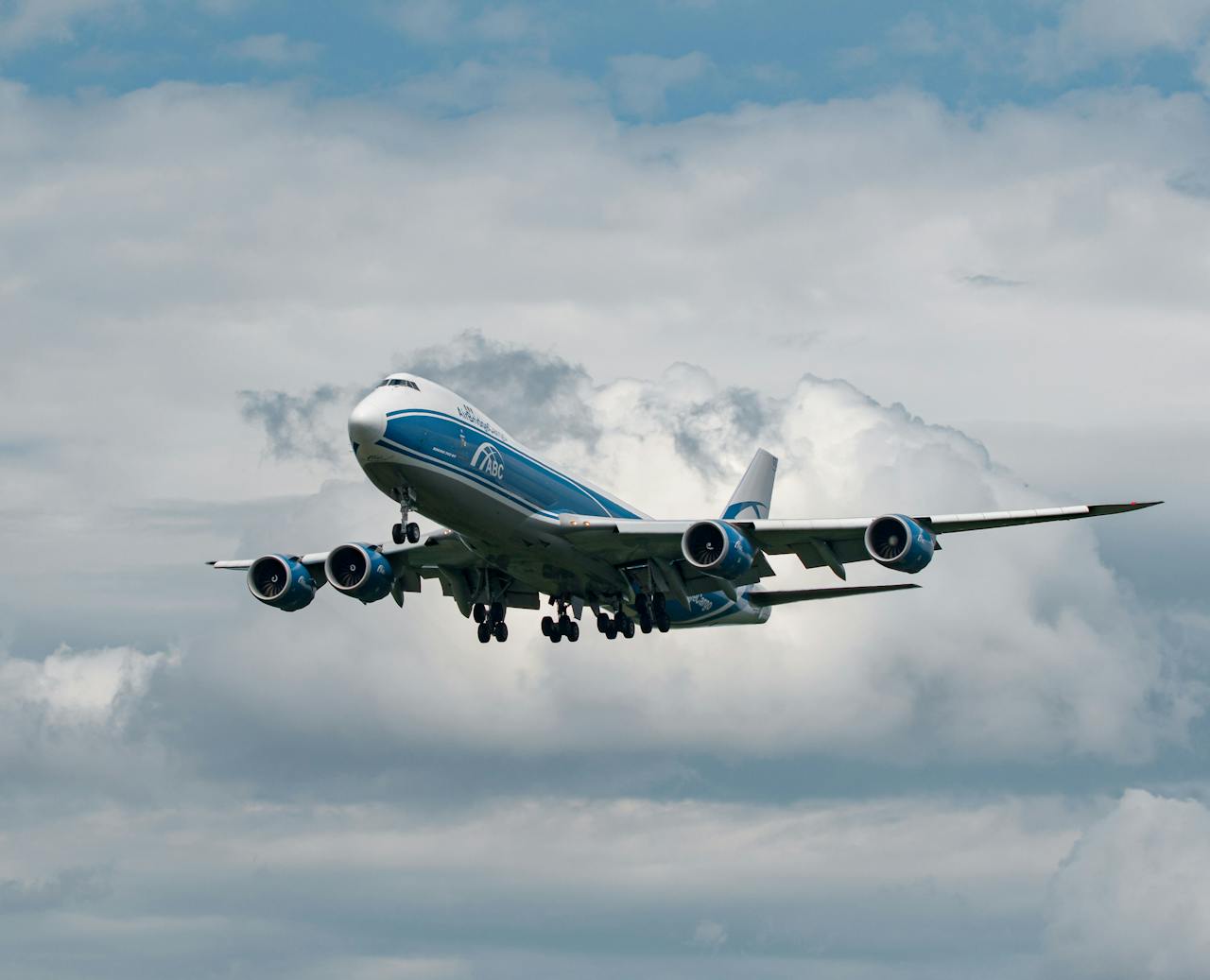 A commercial cargo plane flying against a backdrop of dramatic clouds, showcasing aviation in Frankfurt.